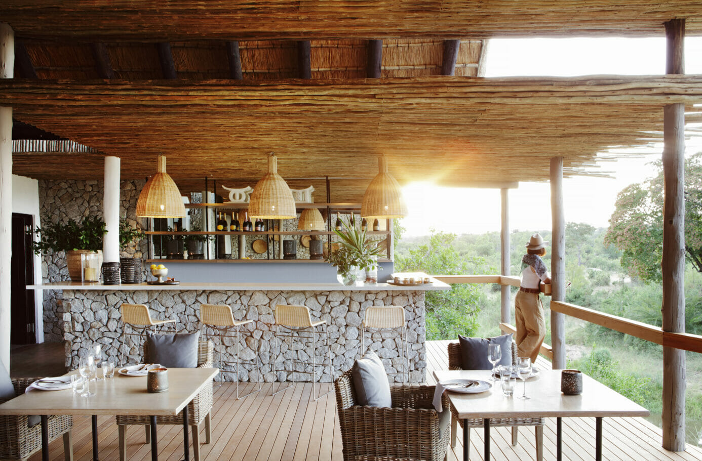 Grey granite stone bar with a white counter top and cream-coloured bar stools overlooking Londolozi Game Reserve river and wilderness