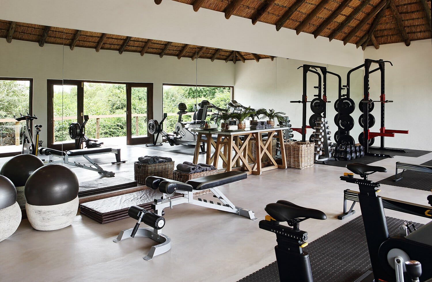 Gym at Londolozi with a mirrored wall, weights, matts, and other fitness equipment.