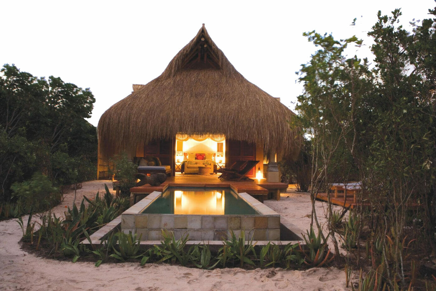 Exterior of infinity beach villa at azura benguerra island a calm rectangular infinity pool leading onto a wooden deck attached to the room