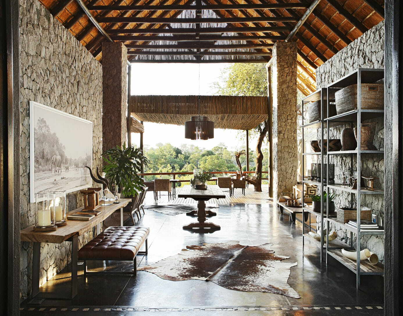 Entrace at Londolozi's Private Granite Suites with granite rock walls, wooden tables, leather seats, and a wooden deck overlooking a canopy of trees