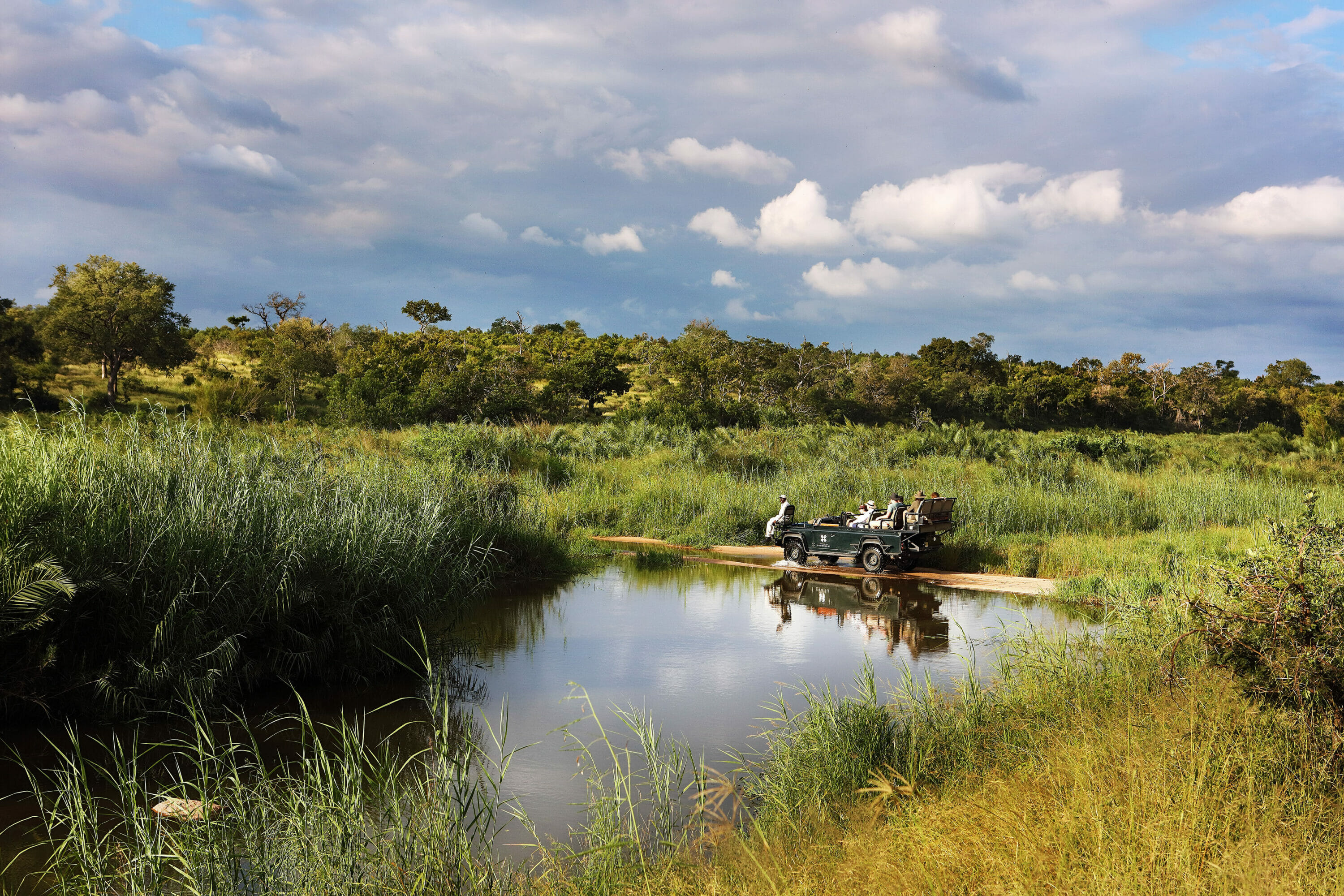 A Land Rover on safari crosses a river, beautiful scenery